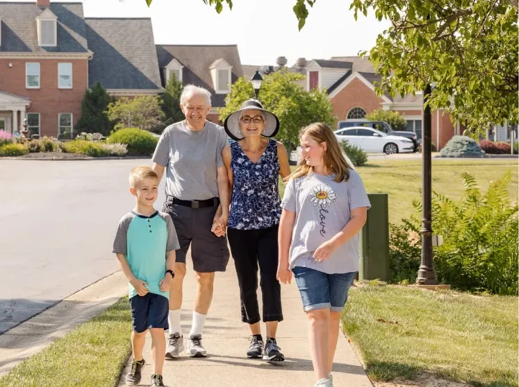 Senior living couple walking outside with their grandchildren