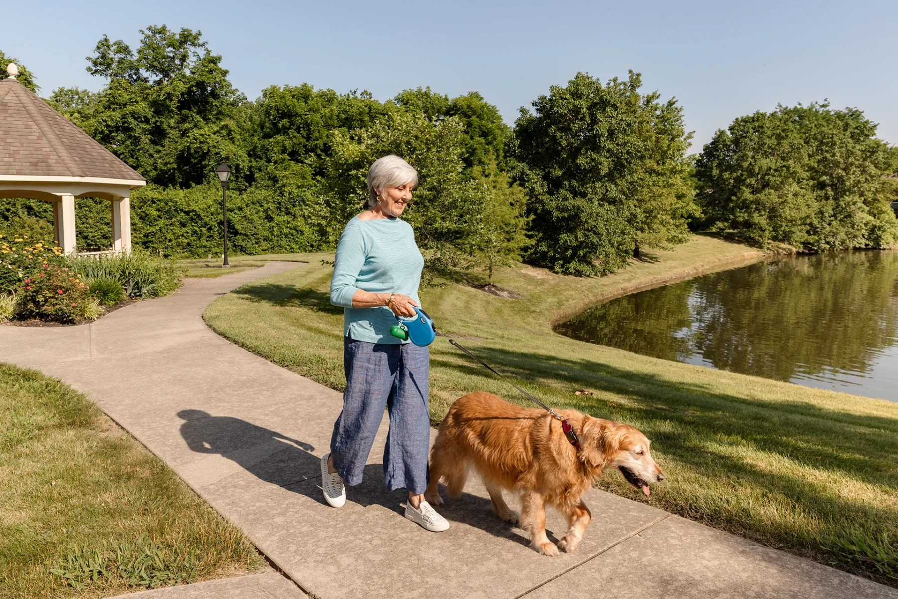 Berkeley Square senior living resident walking her dog outside by the community pond