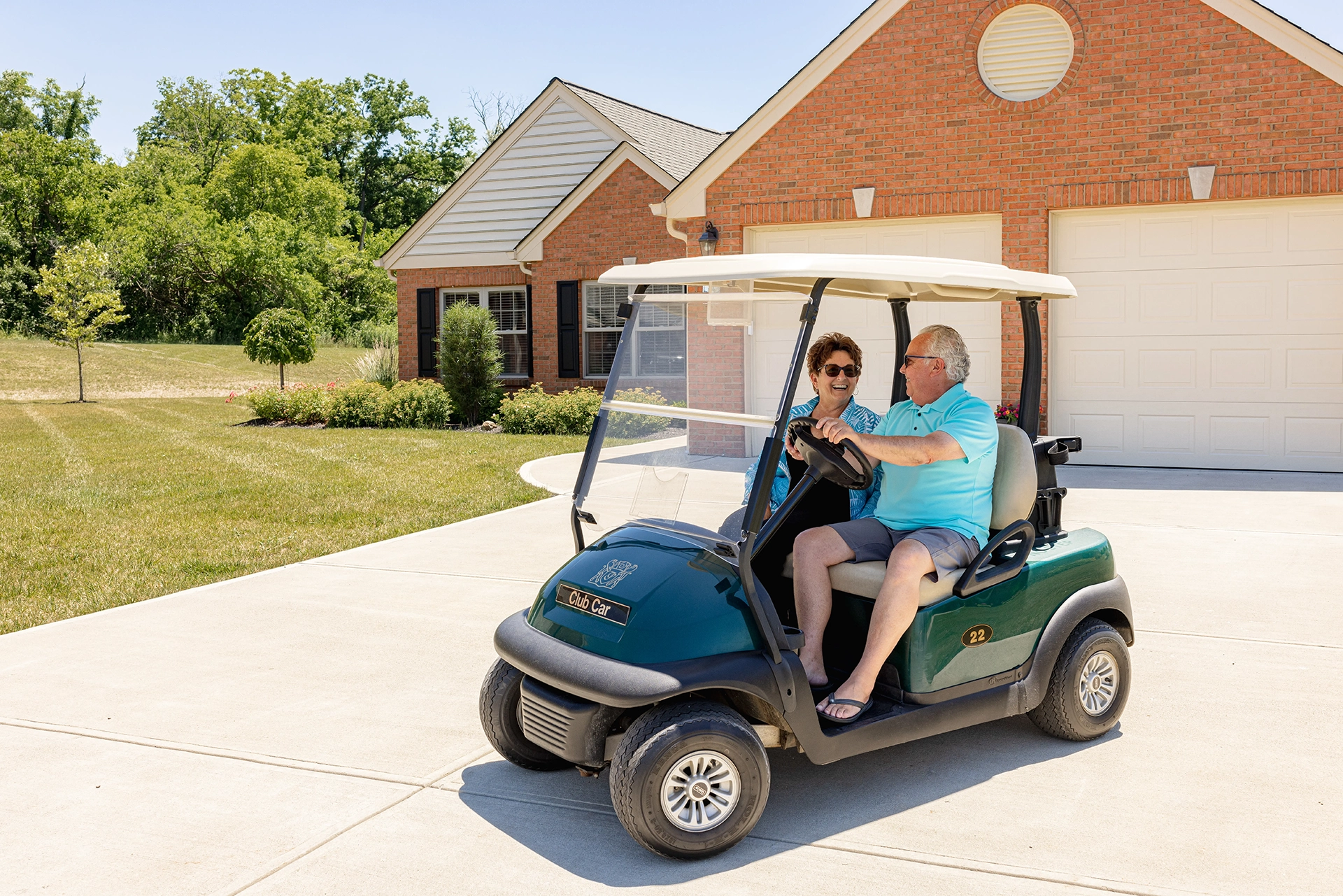 Berkeley Square senior living couple sitting in a golf cart in the driveway of an independent living home