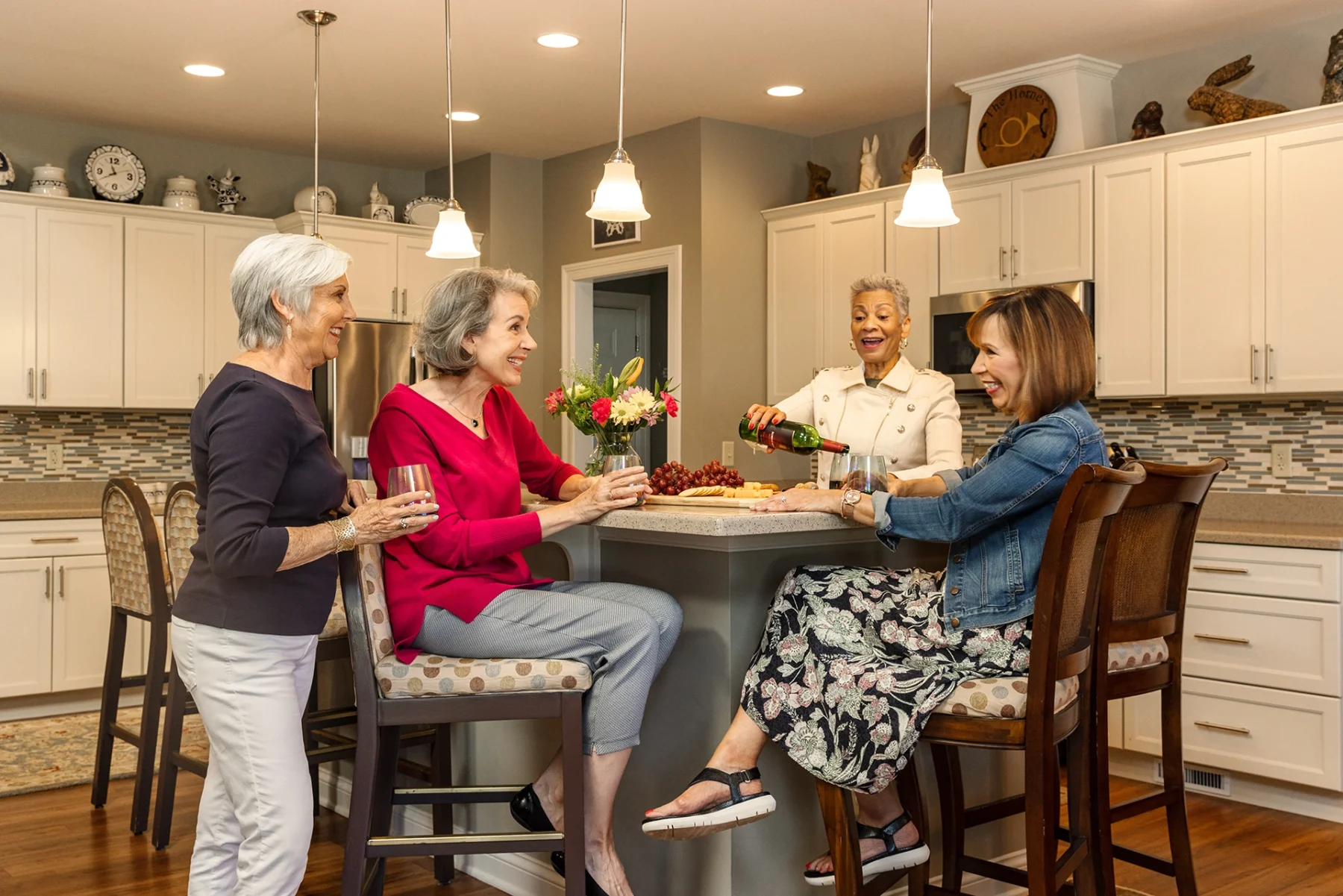 Berkeley Square senior living residents enjoying snacks and drinks in the modern kitchen of an independent living home