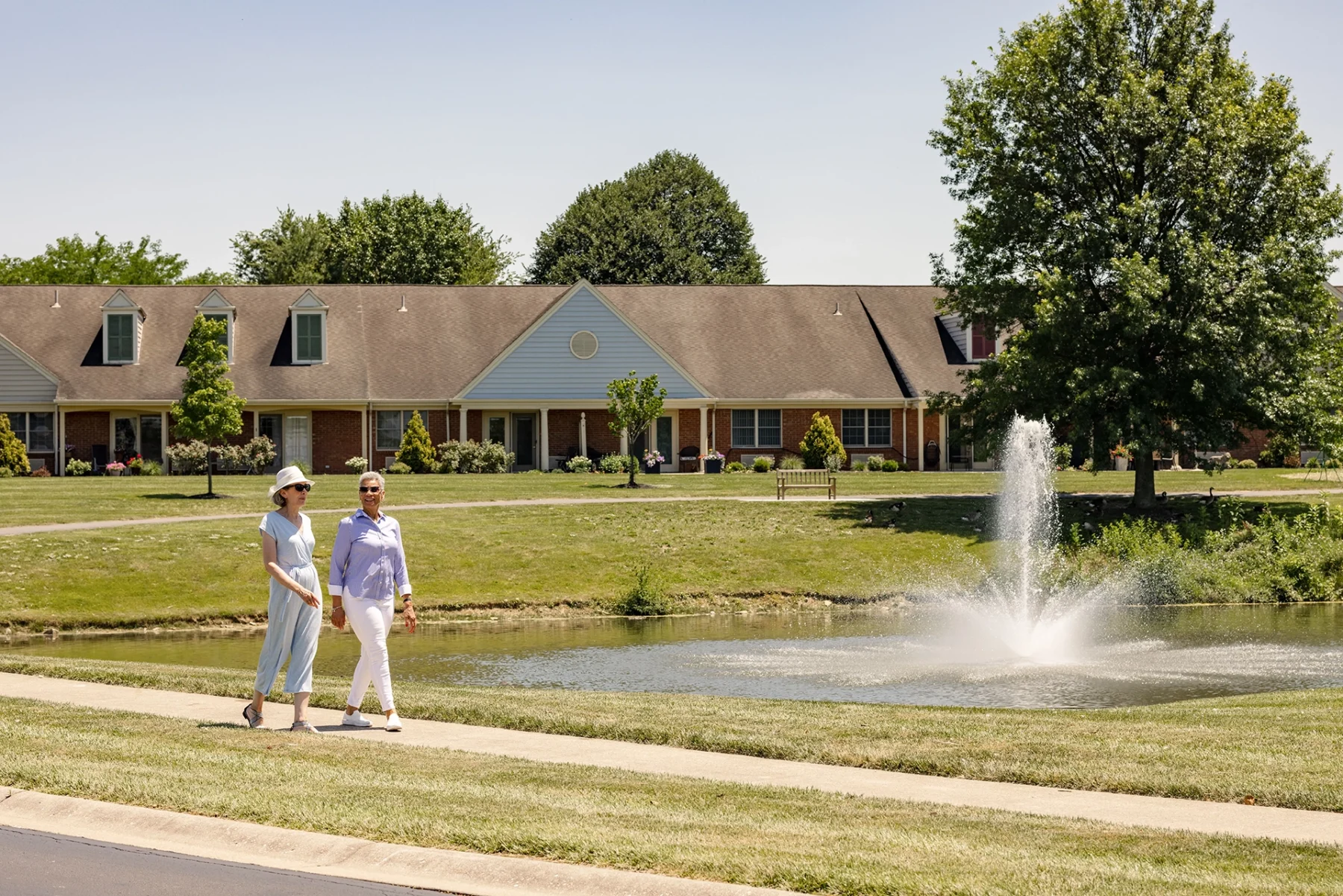 Berkeley Square senior living residents walking outside by a pond in the community