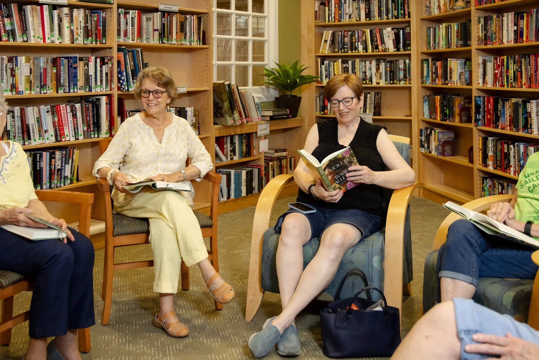 Berkeley Square senior living residents meeting for book club in the community library