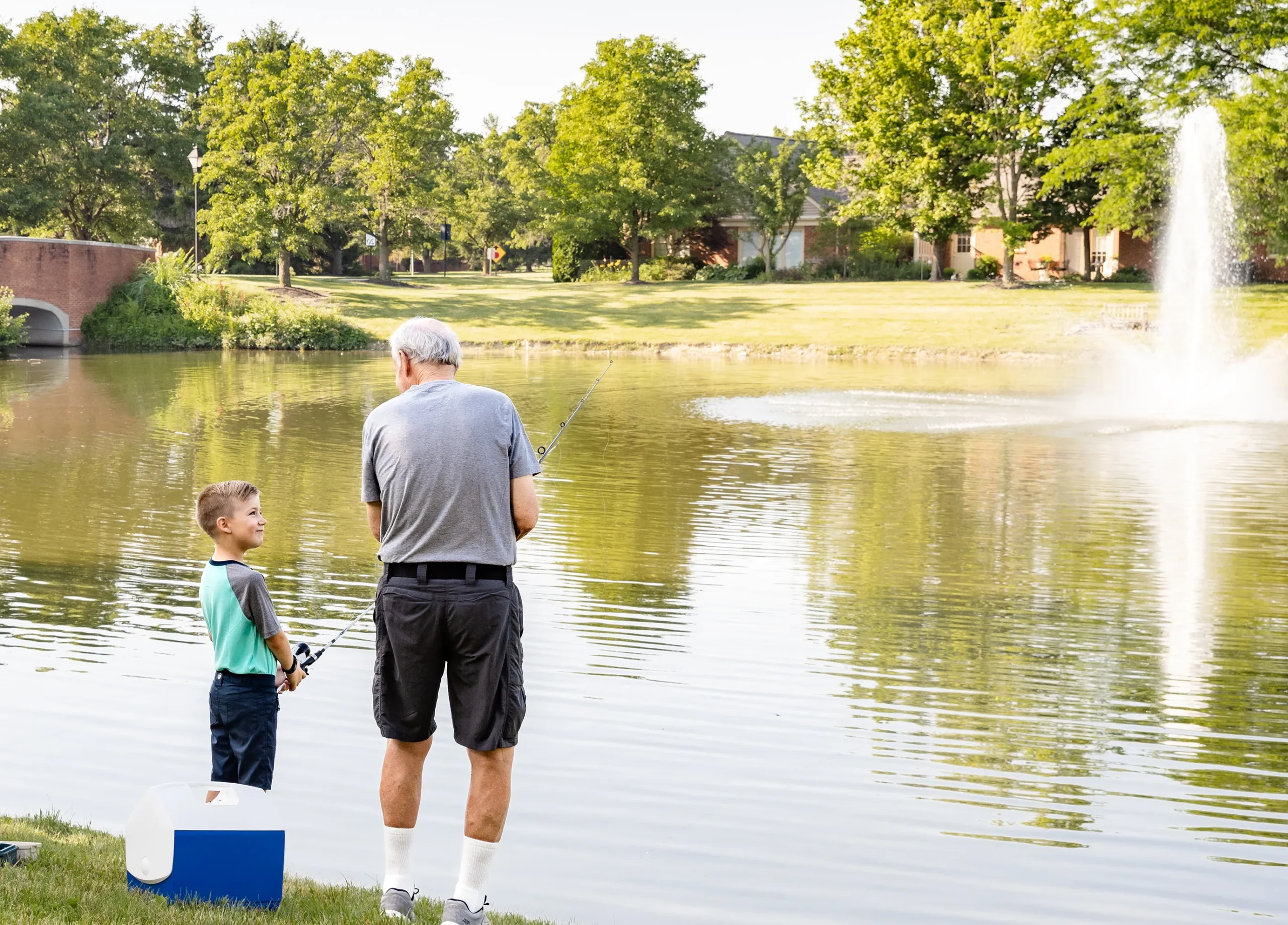 Community First Solutions senior living resident fishing in a pond with his grandson