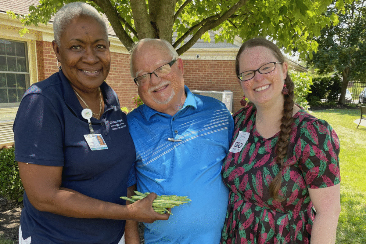 older adult with adult daughter and caregiver in garden